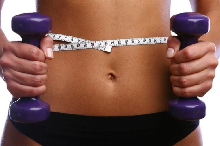 Haltères de fitness entre les mains d'une fille fitige